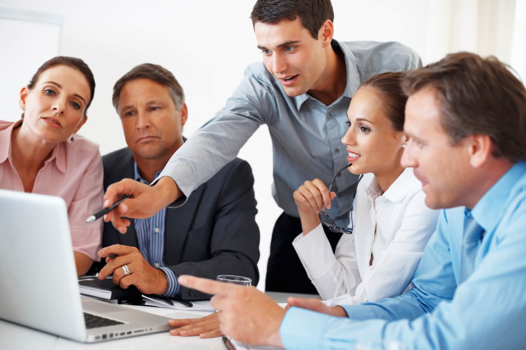 Man pointing to a screen around a meeting room table